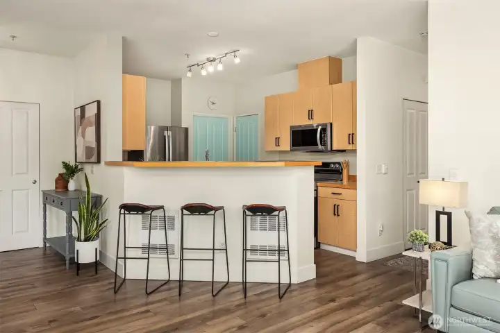 The kitchen's breakfast bar provides a casual and convenient dining option, while the warm cabinetry, modern pendant lighting, and stainless steel appliances create a stylish and highly functional space at the heart of the home.