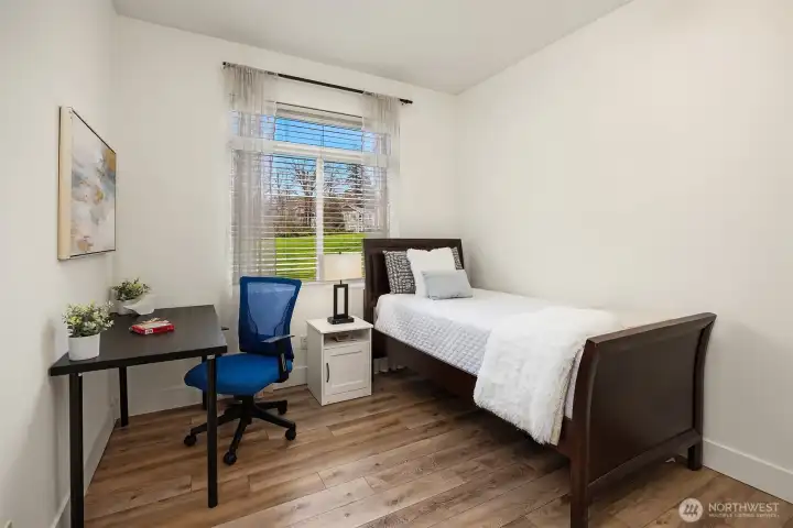 One of the home's additional bedrooms offers a bright and versatile space with a large window, warm flooring, and plenty of room to serve as a guest room, home office, or hobby space.