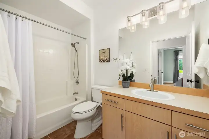 The full bath is clean and well-appointed, featuring a shower/tub combo, warm wood vanity, and bright lighting, a functional and comfortable space serving the additional bedrooms.