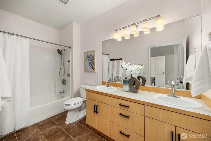 The primary en-suite bath features a shower/tub combo, warm wood vanity with ample counter space, and bright lighting, a clean and well-appointed space that completes this private retreat.
