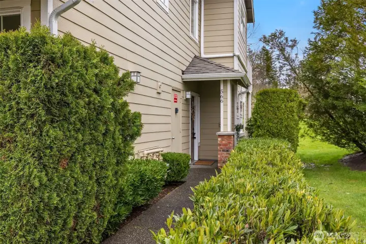 The home's ground-floor entry is framed by lush, mature landscaping, offering easy, step-free access and a welcoming first impression that reflects the beauty of the surrounding Cameray community.