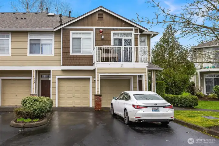 The exterior of this Cameray home showcases classic Pacific Northwest architecture with a private garage, well-maintained landscaping, and an upper-level deck, a polished and inviting curb presence in a beautifully kept community.