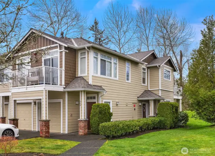 Another view of the home's exterior highlights the attractive multi-level architecture, lush green surroundings, and the private garage, a well-appointed and handsome presence within this sought-after Sammamish community.