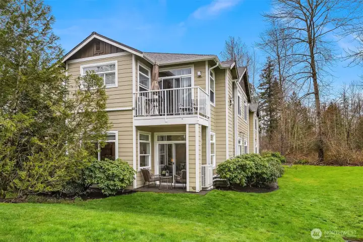 The rear of the home showcases the private ground-floor patio and upper-level deck, both overlooking a serene and expansive green space, a rare and tranquil setting that makes this home truly special.