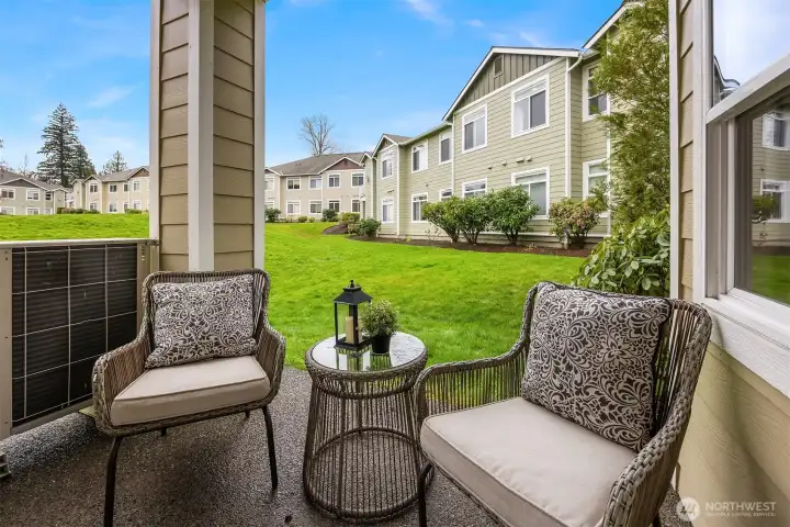 The private ground-floor patio offers a charming outdoor retreat with comfortable seating and direct views of the lush green space beyond, a perfect spot for morning coffee or peaceful evening relaxation surrounded by nature.