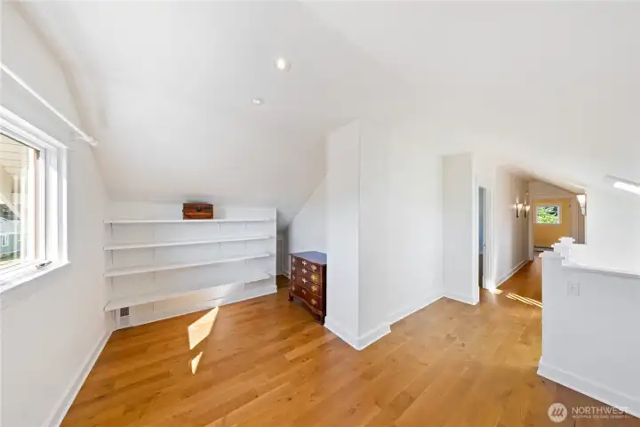 Here is the Art Studio Space.  The space behind is where the built-in storage cabinets are.  The stairs are on the other side of the Pony Wall on the right.  There is additional storage tucked behind the built in shelving on the right side.  You can see the first door on the left opens to a large Bedroom with walk-in closet.  The second upper Bedroom is seen at the end of the hallway.