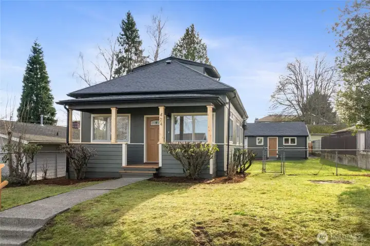 Front Facade with new porch, new roof, gutters and fresh exterior paint. Garage in backdrop.