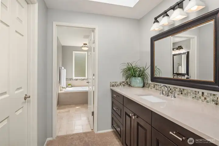 One of 2 vanities in the primary suite. To the left is the door to walk-in closet with custom shelving