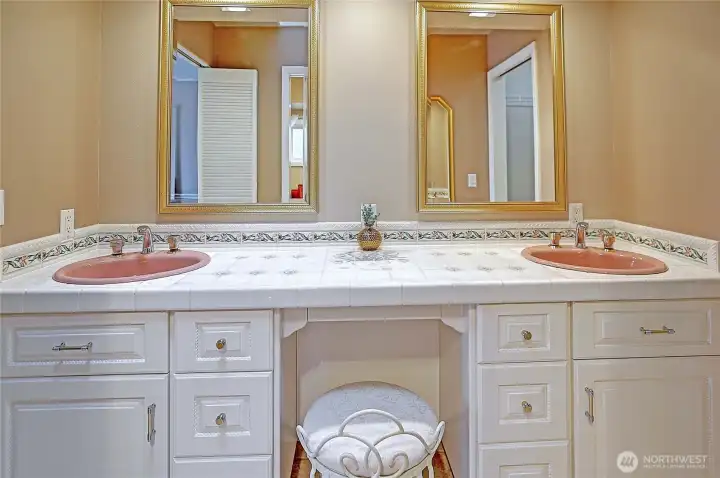 Two sinks sit side by side, quietly mirrored in their purpose. The symmetry feels intentional but not rigid. Nearby, the walk-in shower and adjacent bench sits like a pocket of calm.