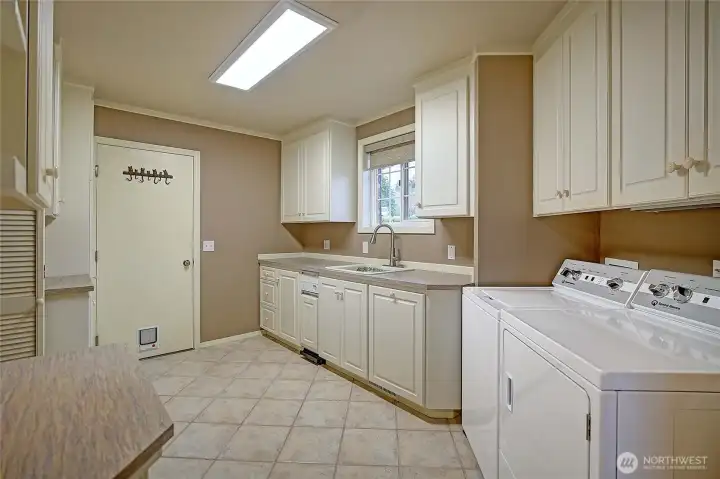 The mud/utility room serves as a spacious, practical entry from the 3 car attached garage, designed to keep daily life organized. It opens into a full walk-in pantry lined with ample shelving, offering generous space for groceries and household essentials.