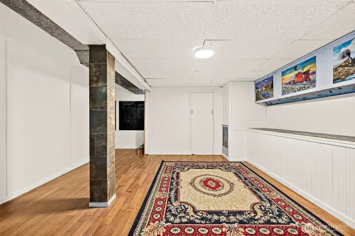 Finished bonus space in basement level with partial hardwood flooring that blends into carpeting on fireplace side.