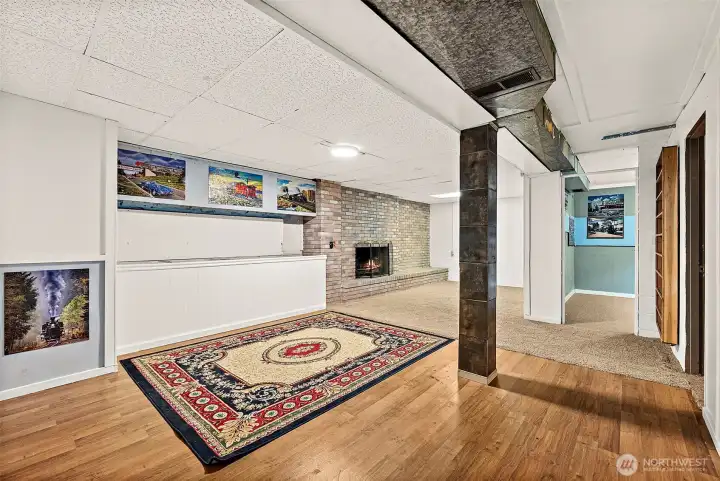 Finished bonus space in basement level with partial hardwood flooring that blends into carpeting on fireplace side. Leading into the lower level bedroom.