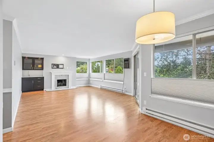 Cheerful dining space with dramatic pendant light and floor-to-ceiling windows framing lush greenery.