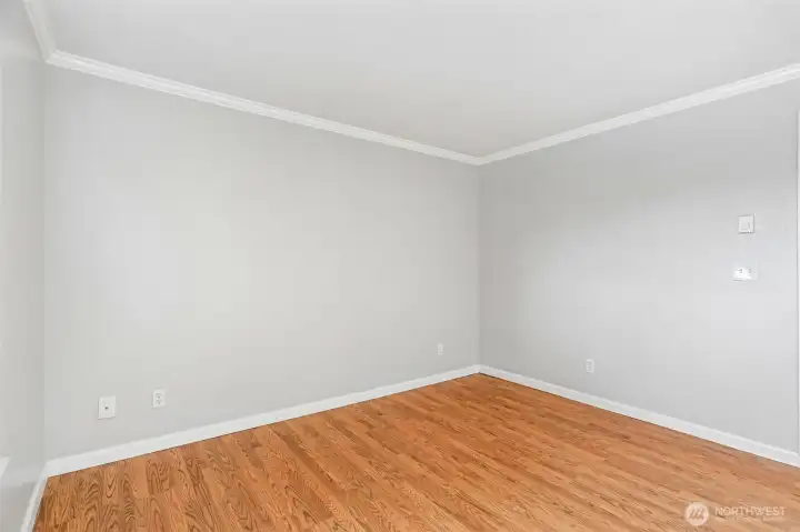 Generously sized room with pristine hardwood floors and a light, airy feel.
