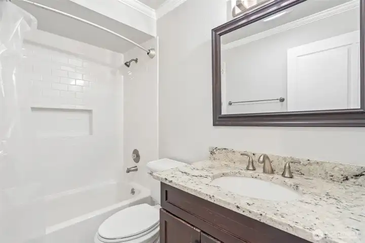 Updated bathroom with double vanity, granite counters, and a relaxing soaking tub.