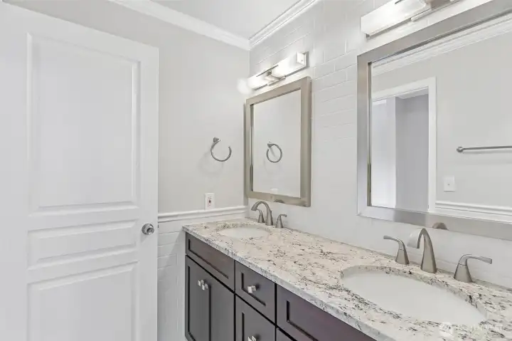 Spa-inspired bathroom with dual sinks, granite countertops, and warm vanity lighting.