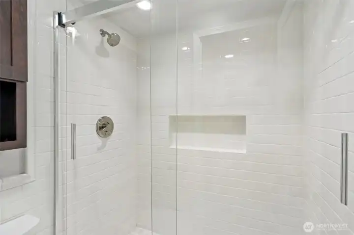 Luxurious walk-in shower with floor-to-ceiling tile and a sleek frameless design.