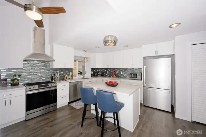 Stunning chef's kitchen with soft-close white cabinetry, stainless steel appliances, quartz countertops, tile backsplash, and luxury vinyl flooring. Stunning chef's kitchen with soft-close white cabinetry, stainless steel appliances, quartz countertops, tile backsplash, and luxury vinyl flooring.