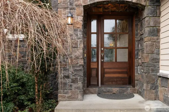 The front entry door is just stunning and has obscured glass and is surrounded by stone.