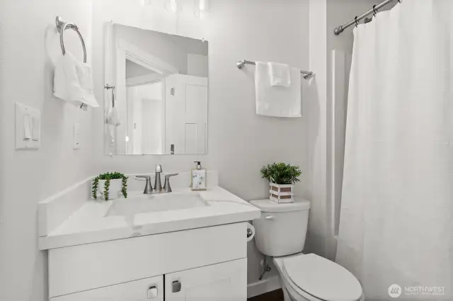 Bright and inviting bathroom featuring quartz counters, contemporary lighting, and a full-size tub