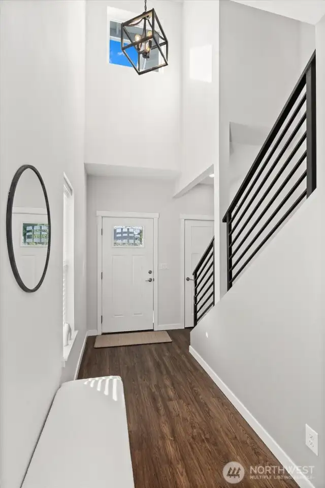 Welcoming entry flooded with natural light, featuring contemporary railings and stylish light fixtures.