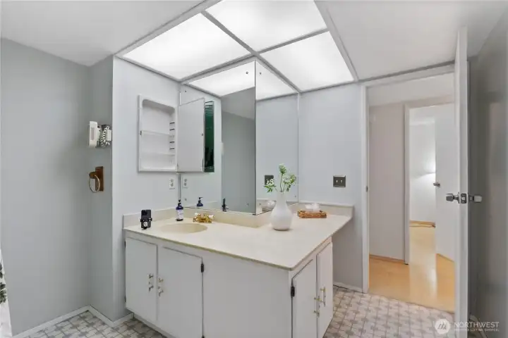 This functional guest bath features a spacious vanity area with abundant counter space and a large mirror, offering a bright and comfortable place to start and end the da