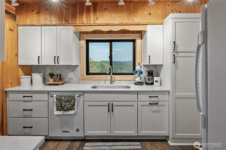 A charming cabin-style kitchen, updated with crisp white cabinetry and quartz countertops, pairs rustic warmth with modern ease.