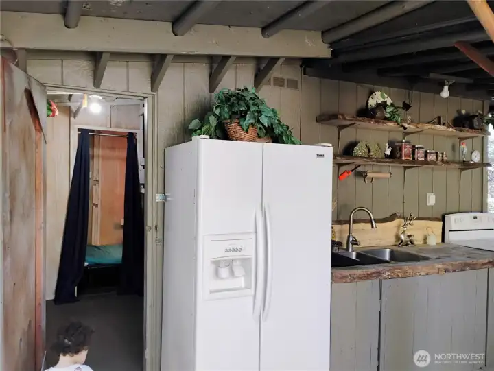 Storage area with workbench and staged bunkhouse to left of outdoor kitchen