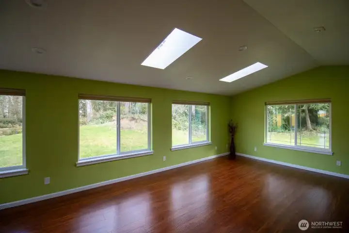 Open living space showcasing skylights, hardwoods, and a wall of windows to the trees Open living space showcasing skylights, hardwoods, and a wall of windows to the trees