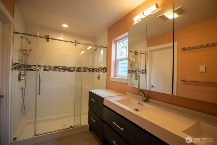 Spa-like primary bath with a double-sink vanity, sliding-glass shower with dual shower heads, and heated floors. Spa-like primary bath with a double-sink vanity, sliding-glass shower with dual shower heads, and heated floors.