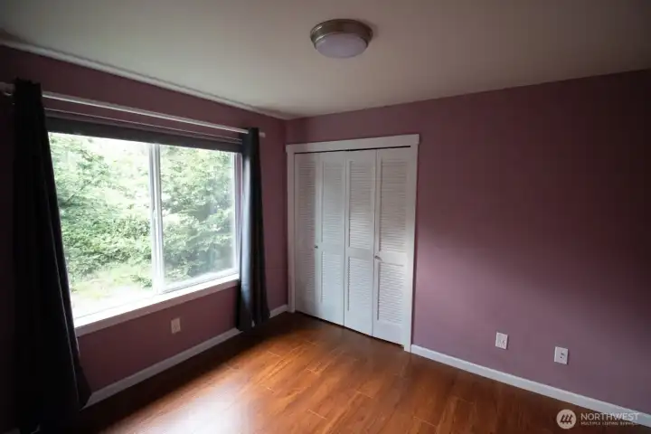Third bedroom with hardwood floors, a double closet, and a large window framing the trees. Third bedroom with hardwood floors, a double closet, and a large window framing the trees.