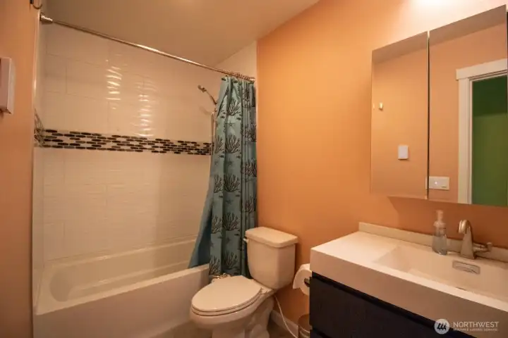 Second bathroom featuring modern vanity, tub-shower combo, tile accent, and warm heated floors. Second bathroom featuring modern vanity, tub-shower combo, tile accent, and warm heated floors.