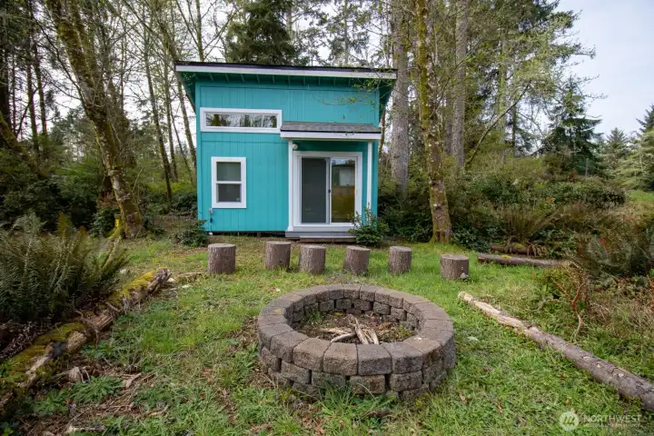Detached studio nestled among the trees, with a stone firepit and log-stump seating — a private retreat. Detached studio nestled among the trees, with a stone firepit and log-stump seating — a private retreat.