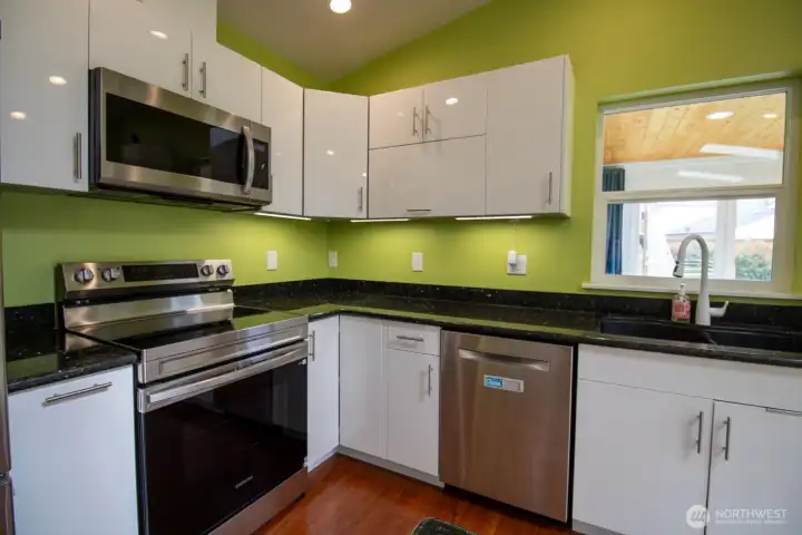 Kitchen close-up highlighting stainless appliances, granite counters, and glossy white cabinetry. Kitchen close-up highlighting stainless appliances, granite counters, and glossy white cabinetry.
