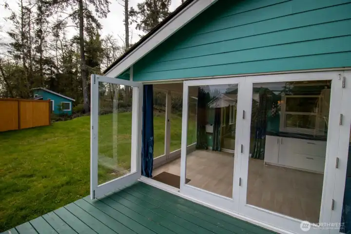 Sunroom's glass doors open wide to the back deck — seamless indoor-outdoor living for entertaining. Sunroom's glass doors open wide to the back deck — seamless indoor-outdoor living for entertaining.