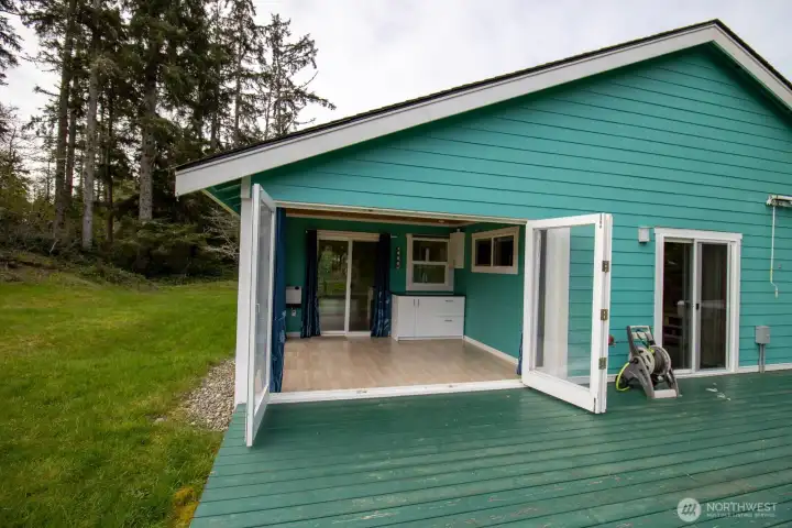 Sunroom's glass doors fold fully open across the back wall — blending the room seamlessly with the deck and yard. Sunroom's glass doors fold fully open across the back wall — blending the room seamlessly with the deck and yard.