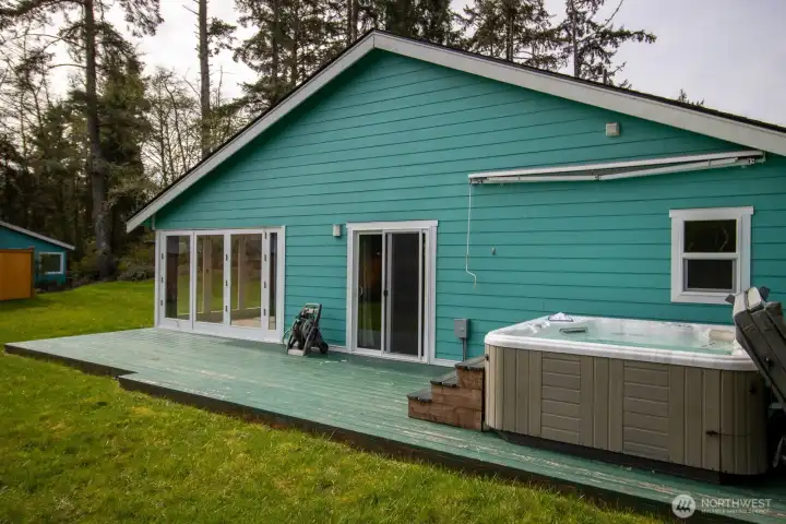 Expansive back deck with a hot tub and a retractable awning overhead — soak comfortably even on rainy days. Expansive back deck with a hot tub and a retractable awning overhead — soak comfortably even on rainy days.