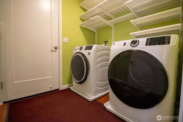 Laundry area with a new front-load washer and dryer and built-in storage shelving. Laundry area with a new front-load washer and dryer and built-in storage shelving.