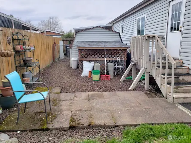 Large Patio Area in the Fully Fence Pet Friendly Backyard Showing Storage Shed.