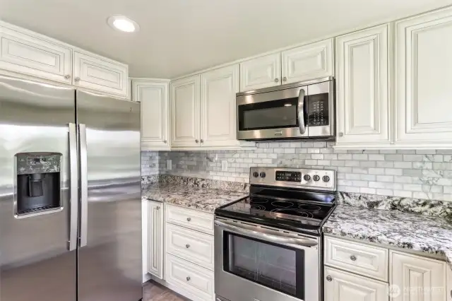 Granite counter tops w/stainless steel appliances in kitchen