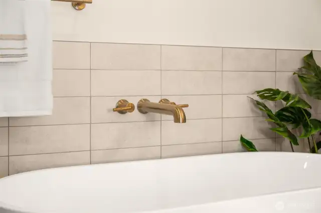 Deep soaking tub and custom tile surround elevate the bathing experience. A perfect spot to unwind with a candle and a book after a long day.
