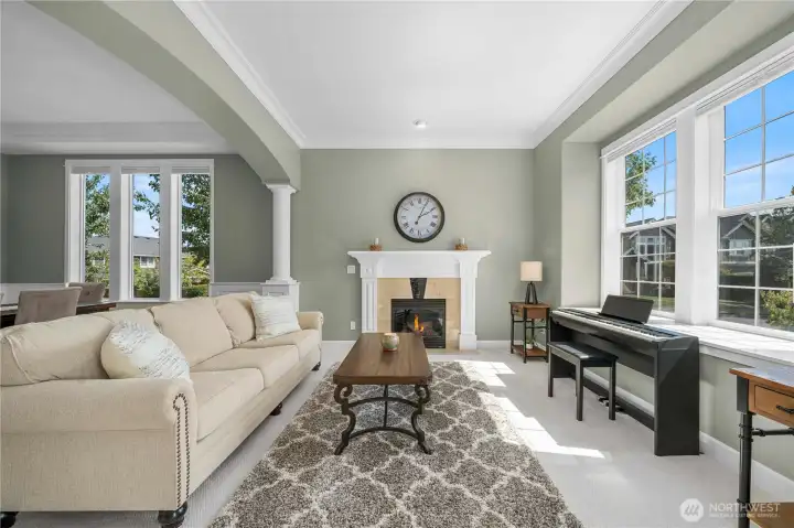 Elegant living room with abundant natural light, a cozy fireplace, and open flow to the dining area.
