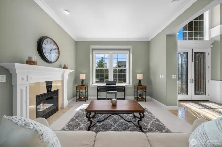 Expansive picture window floods the living space with light, highlighting the fireplace and welcoming entry.
