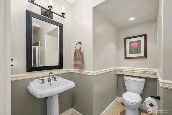 Elegant main-level 3/4 bathroom with pedestal sink, updated lighting, and shower.