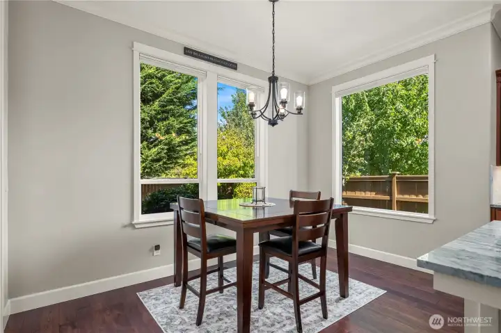 Bright dining nook with large windows, chandelier, and views of the private backyard.