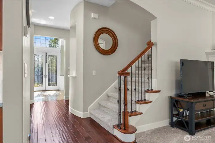 Elegant staircase with wrought iron railing and wood accents, framed by natural light from the entry.