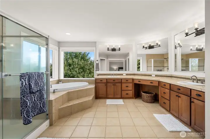 Luxurious primary bath with dual vanities, makeup station, soaking tub, walk-in shower, and abundant natural light.