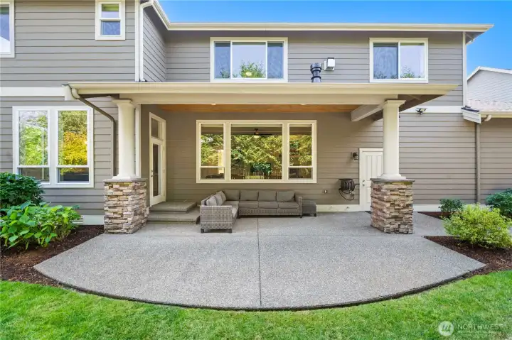Spacious covered patio with stone-accented columns and private backyard views, perfect for year-round entertaining.