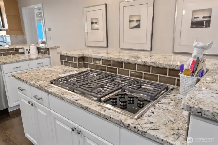 The five-burner gas cook top is located on the kitchen island.