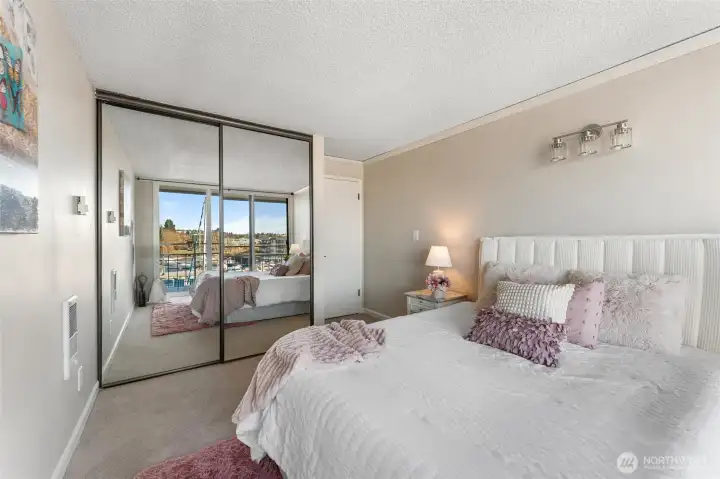 Alternate view of the primary bedroom highlighting mirrored closets and abundant light.